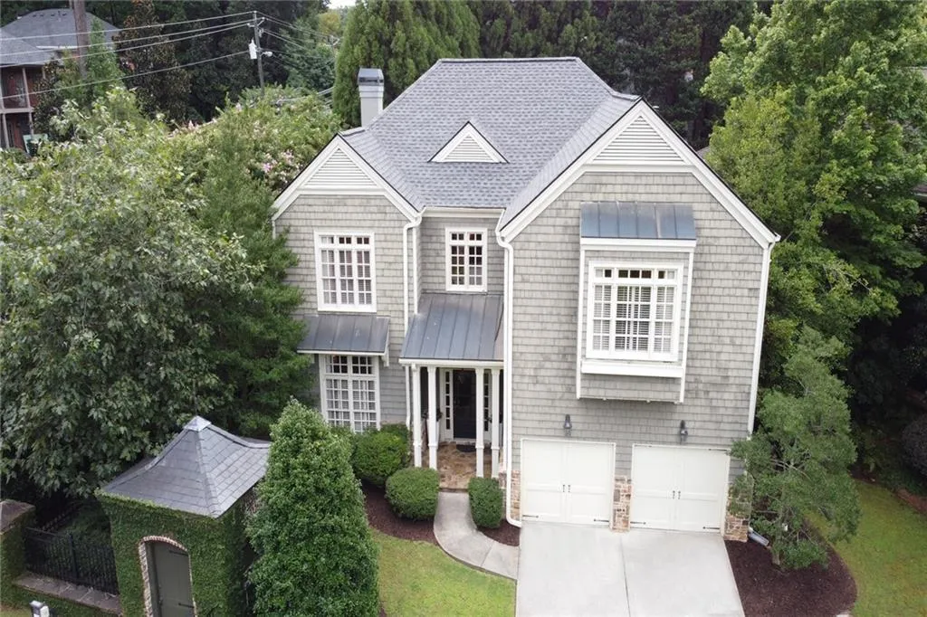 View of front facade with a standing seam roof, a metal roof, concrete driveway, a chimney, and a garage
