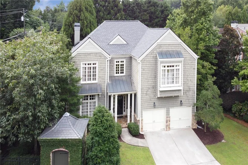 View of front of home featuring a standing seam roof, a metal roof, driveway, a chimney, and an attached garage
