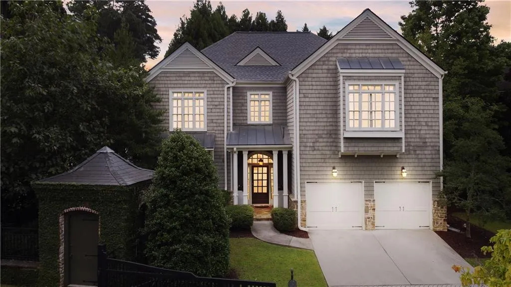 View of front of home with a standing seam roof, a metal roof, concrete driveway, stone siding, and an attached garage