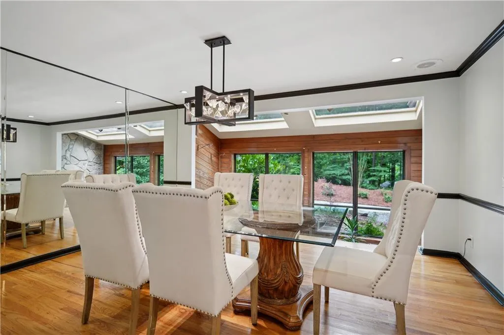 Dining area featuring ornamental molding, light wood-type flooring, and a skylight