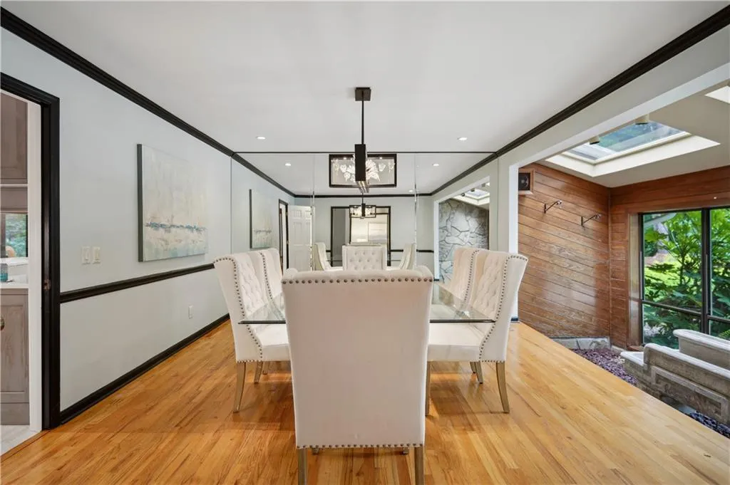 Dining space featuring light hardwood / wood-style floors, crown molding, a skylight, and an inviting chandelier