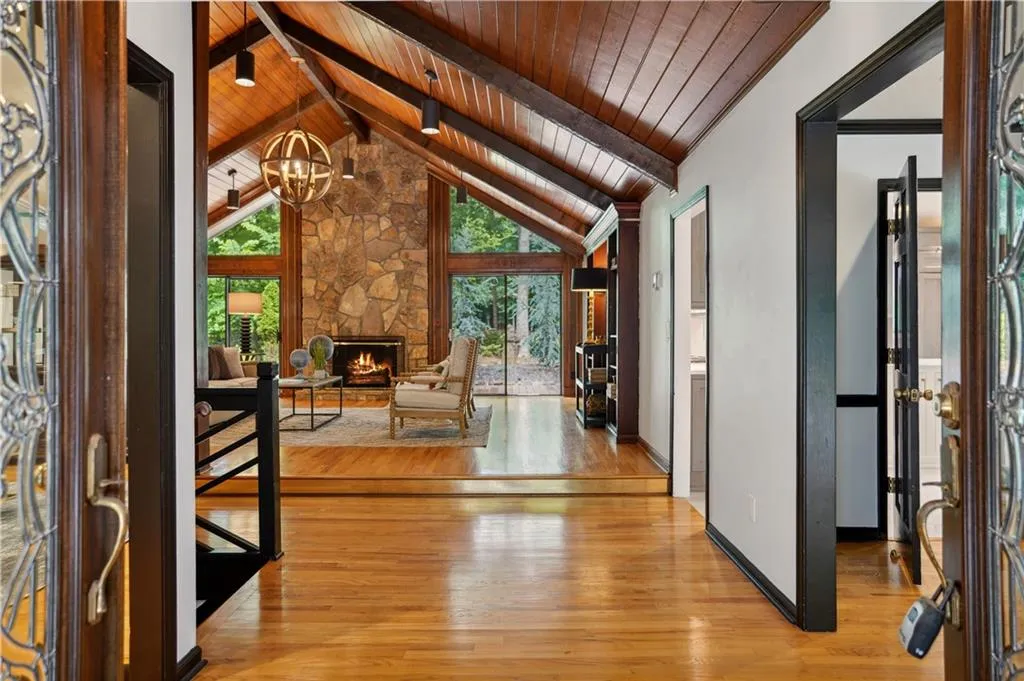 Foyer entrance featuring beamed ceiling, wooden ceiling, a stone fireplace, and light wood-type flooring