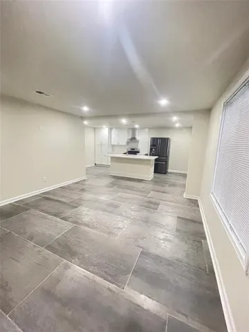Open concept living space featuring large format tile flooring, recessed lighting, a kitchen island, white cabinetry, and stainless steel appliances