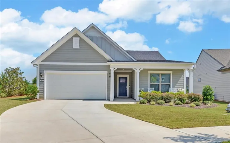 Single-story residence featuring a covered front porch, attached garage, concrete driveway, and established front landscaping