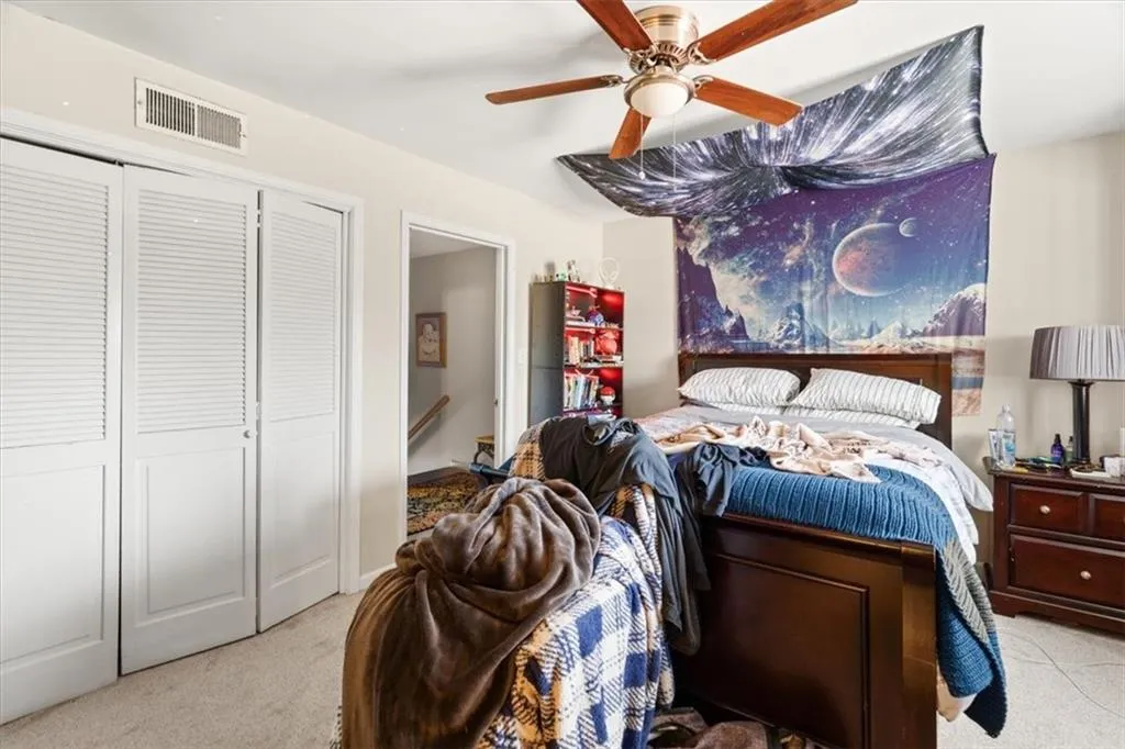 Bedroom featuring a closet, ceiling fan, and light colored carpet