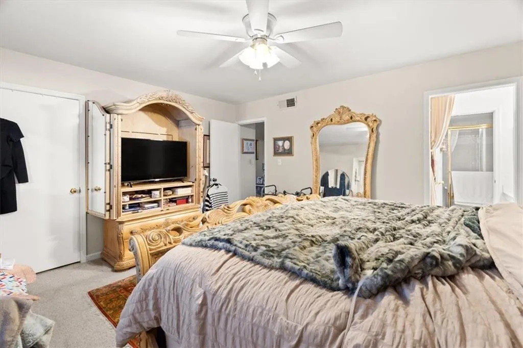 Carpeted bedroom featuring a ceiling fan and ensuite bathroom