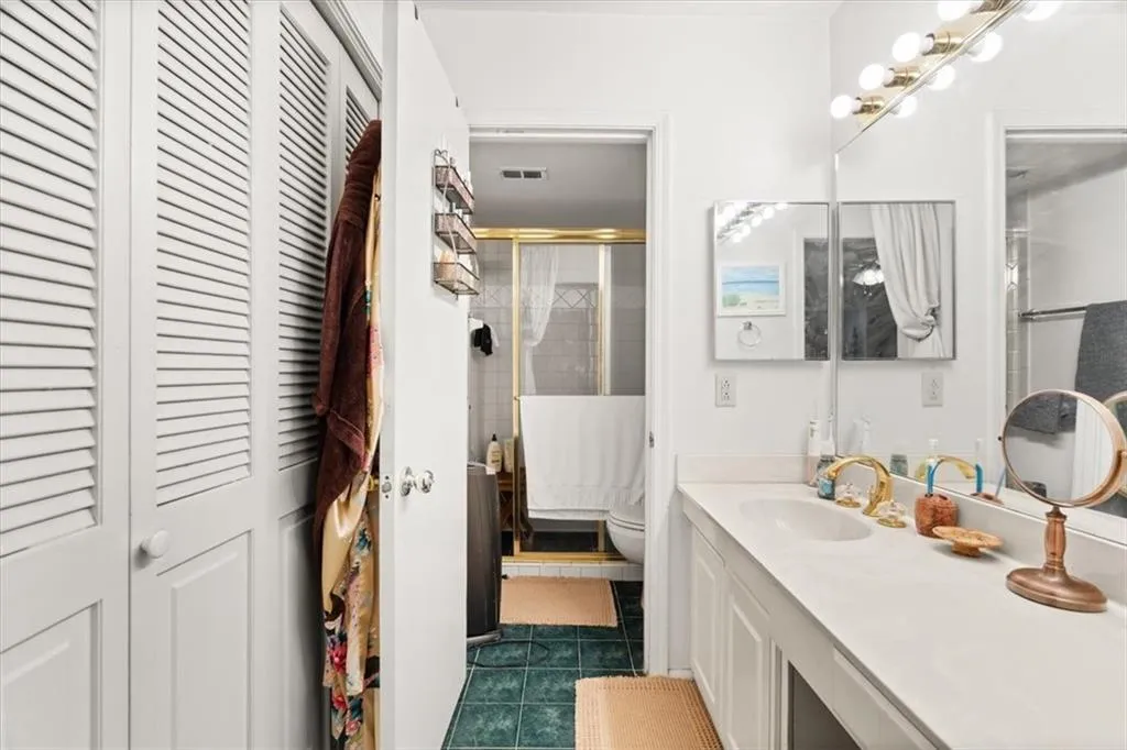 Full bath with a closet, vanity, a stall shower, and dark tile patterned floors