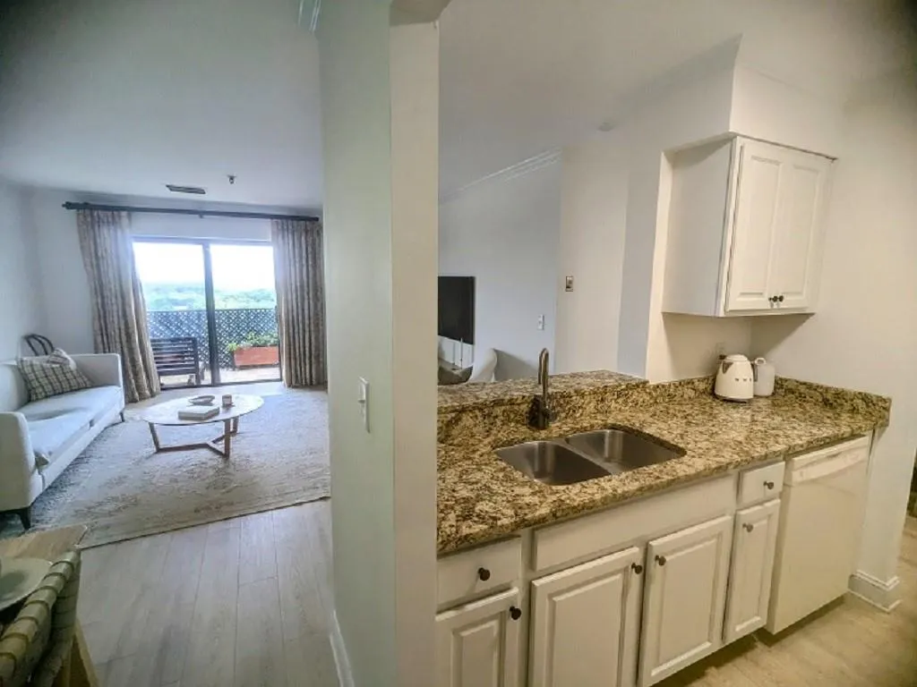 Kitchen featuring white cabinetry, sink, white dishwasher, light stone countertops, and light hardwood / wood-style flooring