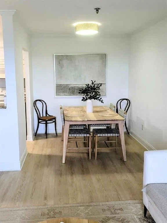 Dining space featuring wood-type flooring and crown molding