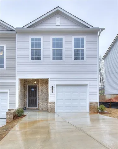 Contemporary townhouse facade featuring light-toned horizontal siding and a prominent gable roof