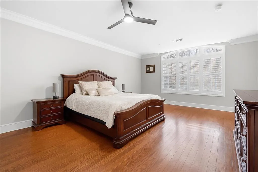 Bedroom with ceiling fan, hardwood floors and crown molding.