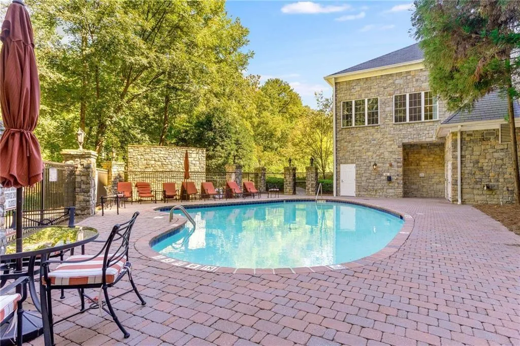 Greystone's saltwater swimming pool. The pool patio has a grilling area. The building in the background is the amenities building. The windows are for the club room, and the lower level has bathrooms with showers and locker rooms.
