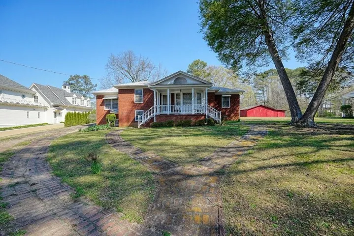 View of front of home with a front lawn, a porch, and brick siding