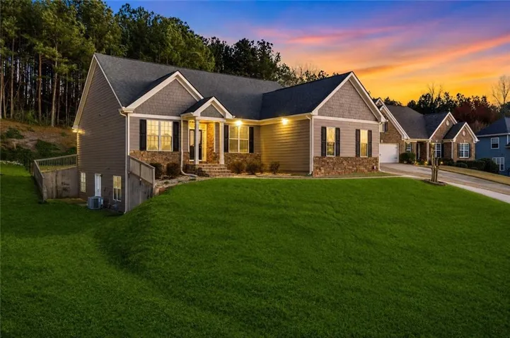 Exterior featuring siding and stone accents, a dark-toned roof, and an expansive front lawn