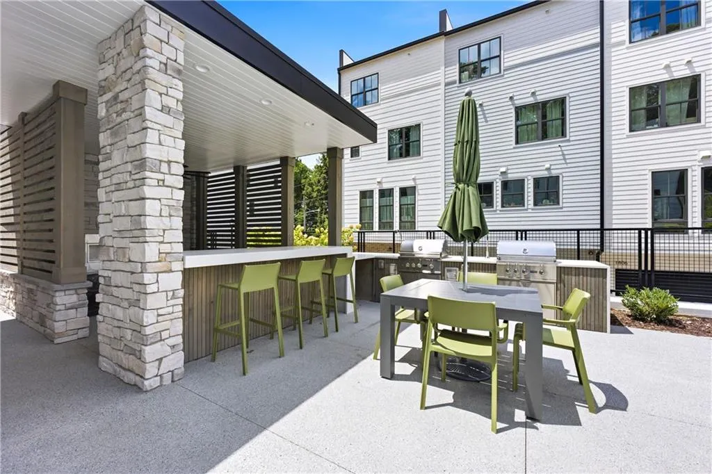 Covered outdoor kitchen featuring a stone-clad bar, built-in grilling stations, and a spacious patio with composite flooring