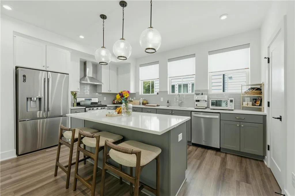 Kitchen featuring wood-finish flooring, white cabinetry, a center island with countertop seating, and stainless steel appliances