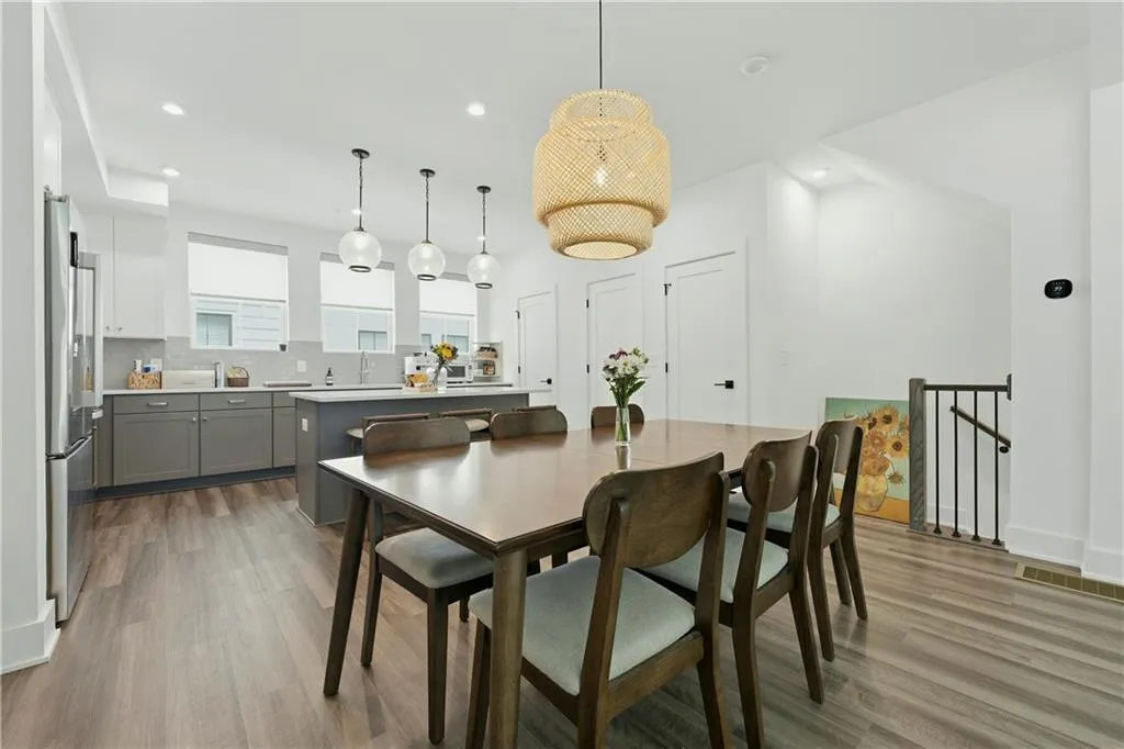 Open-concept dining area with wood-finish flooring, recessed lighting, and a unique pendant light fixture