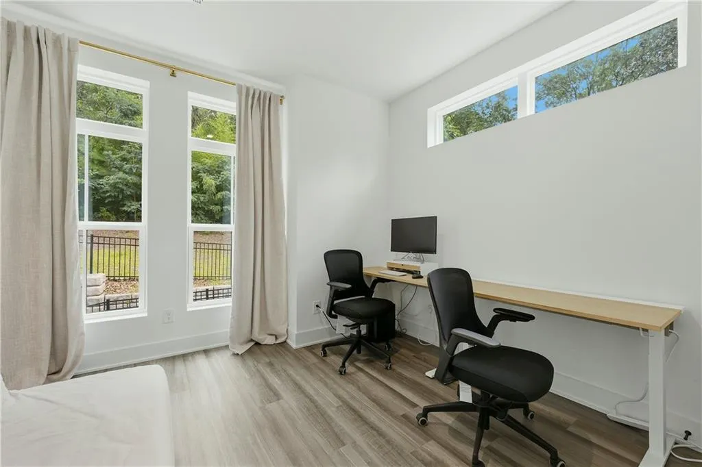 Room with wood-finish flooring, white walls, and multiple windows