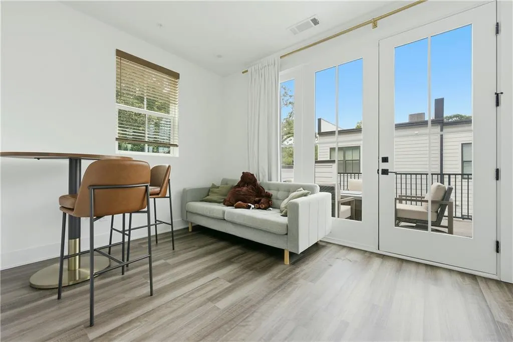 Wood-finish flooring throughout, white walls, and a large window with blinds
