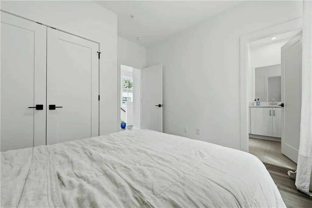 White walls, two white doors with black hardware, recessed lighting, and wood-finish flooring