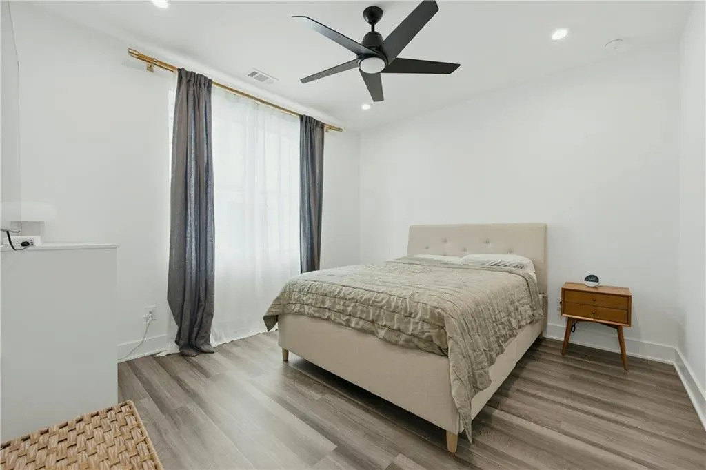 Recessed ceiling lighting, a black ceiling fan, and wood-finish flooring