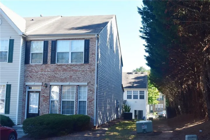 Two-story townhouse with a brick and siding facade, featuring dark window shutters and a front entry door