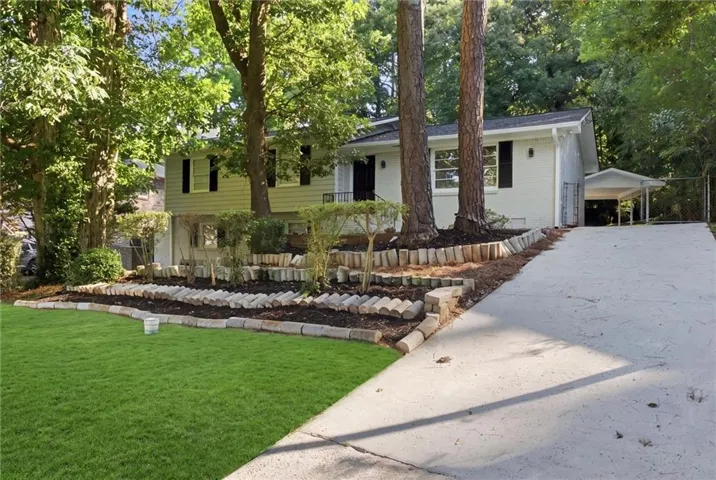 Split-level exterior with a carport, concrete driveway, and tiered landscaping