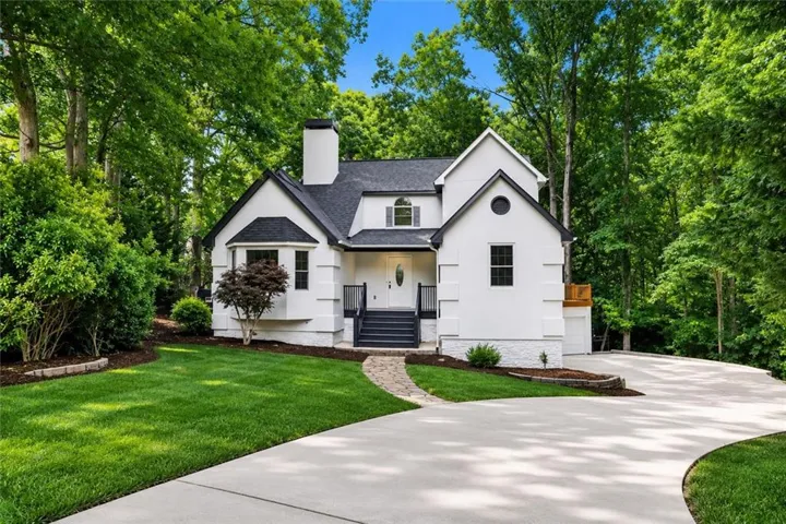 Contemporary white facade with a dark shingled roof, featuring a bay window, covered entry, and a prominent chimney