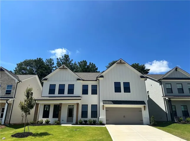 Contemporary farmhouse-style exterior with a two-car garage, dark-framed windows, and a covered entry with timber columns