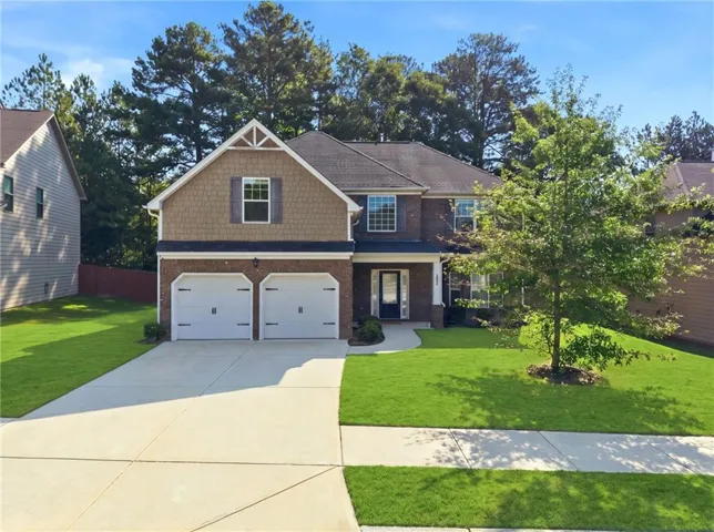 Brick and shingle exterior with a prominent gable, attached two-car garage, and a concrete driveway