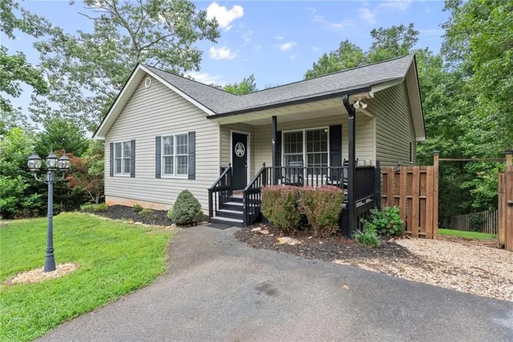 Exterior featuring light-colored horizontal siding, a dark asphalt shingle roof, and a covered front porch with dark railings and steps