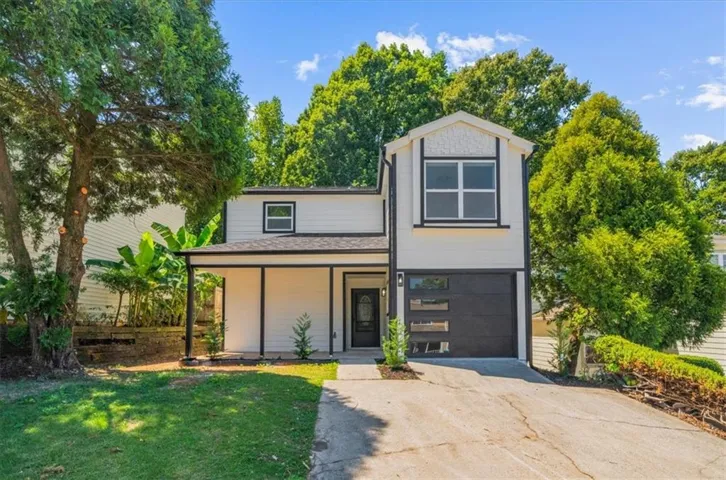 Contemporary exterior with white siding and black trim, featuring a covered entry, a modern garage door with frosted glass panels, and a concrete driveway
