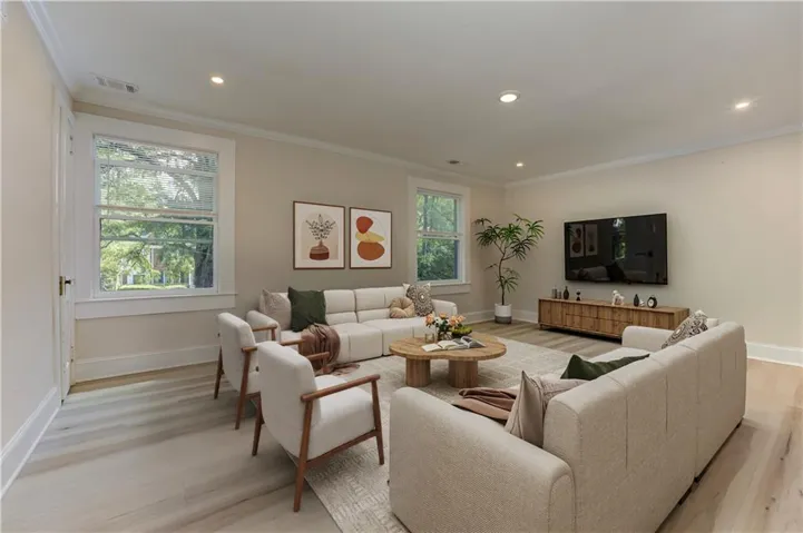 Spacious living area featuring light wood-finish flooring, recessed lighting, and crown molding