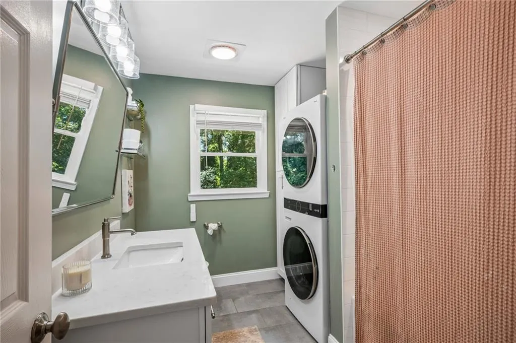 Integrated laundry appliances, single vanity with a white countertop and undermount sink, brushed nickel faucet, and a wall-mounted light fixture