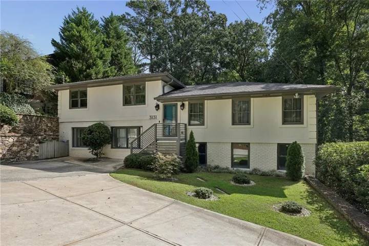Split-level residence featuring a light-colored exterior with brick detailing
