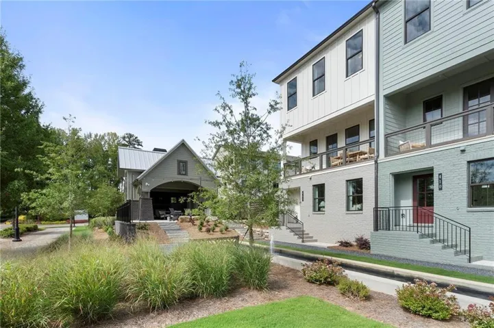 Modern townhome facade with a red entry door, black-framed windows, and cable railings on upper-level balconies
