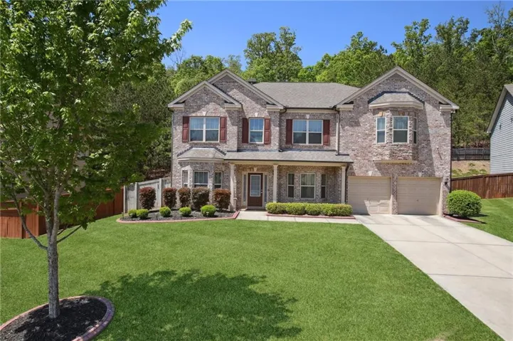 Brick veneer exterior with a two-car garage, covered entry porch, and mature landscaping