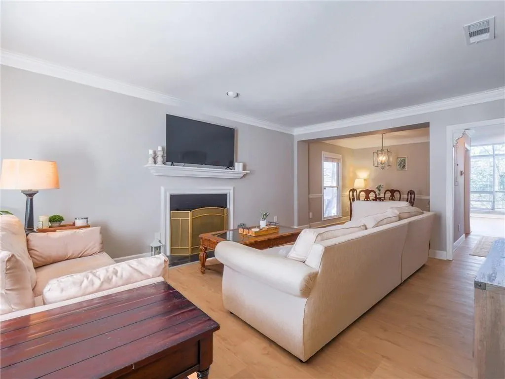 Living area with light wood-style flooring, ornamental molding, a fireplace, and a chandelier