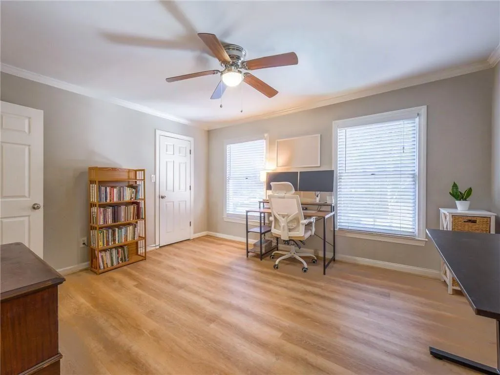 Office space with ornamental molding, light wood-style flooring, and ceiling fan