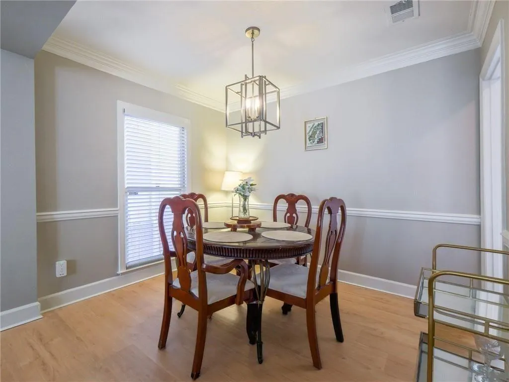 Dining area featuring light wood finished floors, ornamental molding, and a chandelier