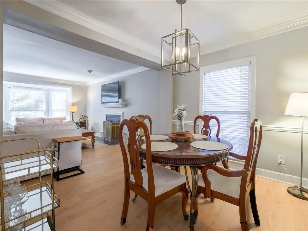 Dining area featuring light wood-style flooring, a fireplace, crown molding, and a chandelier