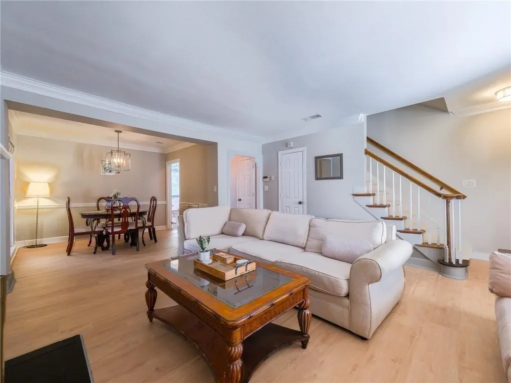 Living area with ornamental molding, light wood-style floors, stairs, and a chandelier