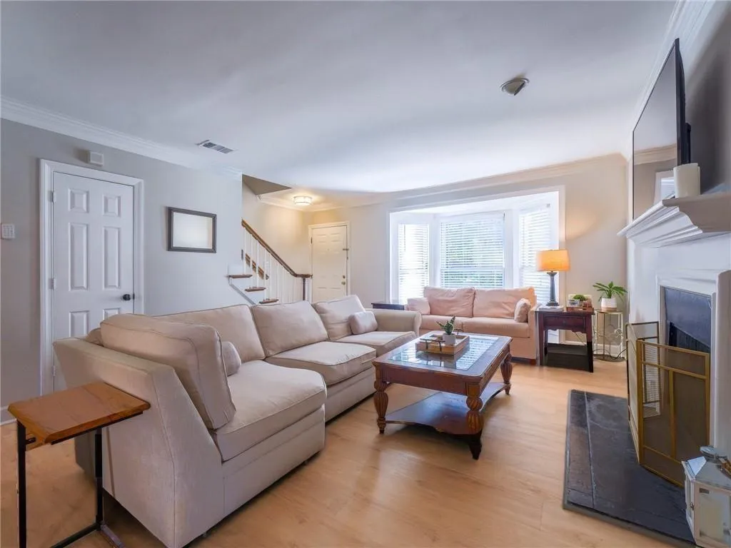Living area featuring ornamental molding, light wood-style flooring, a fireplace, and stairway