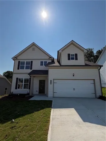Two-story exterior with light-toned siding, attached front-facing garage, dark-toned shutters, and a concrete driveway
