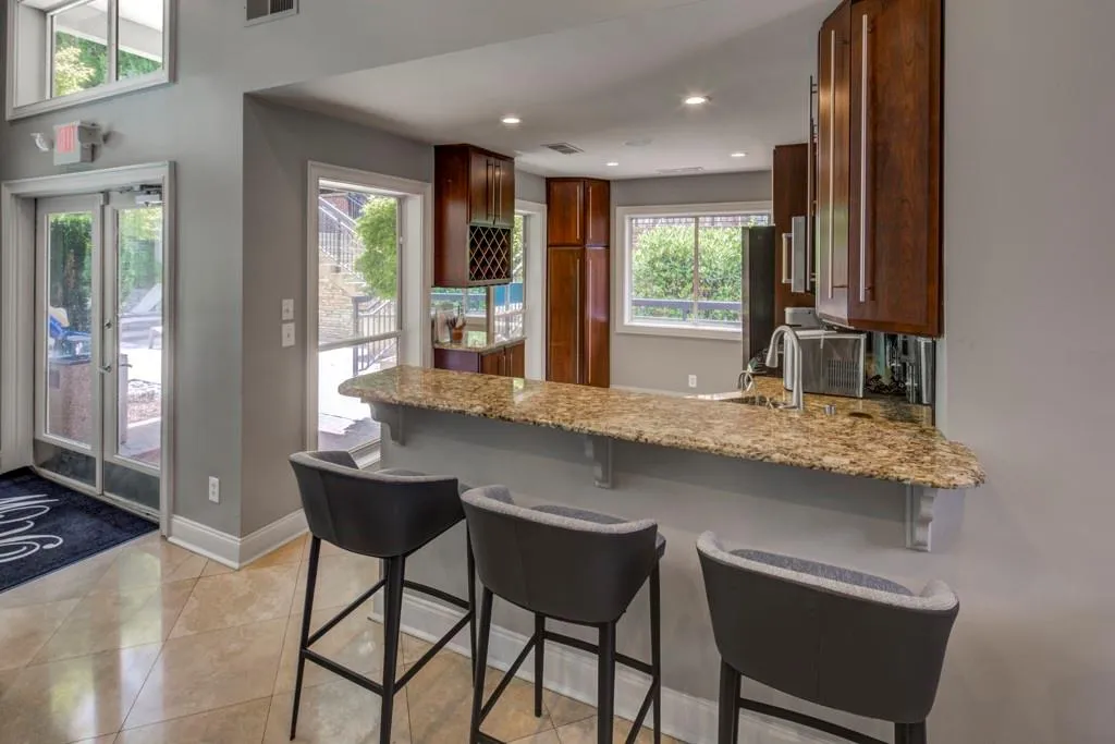 Kitchen featuring a breakfast bar, a peninsula, light stone counters, recessed lighting, and light tile patterned flooring