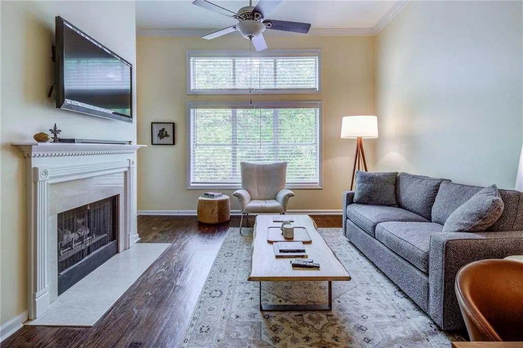 Living room featuring ornamental molding, a ceiling fan, dark wood-type flooring, and a fireplace
