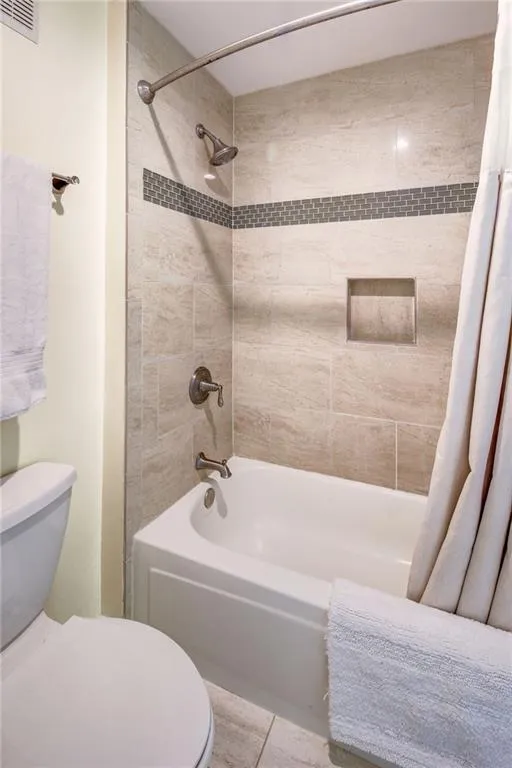 Full bathroom with shower / tub combo with curtain and light tile patterned flooring