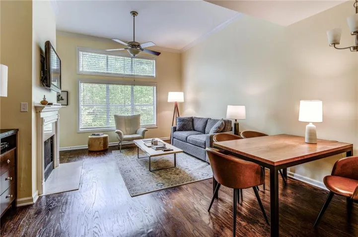 Living area featuring ornamental molding, dark wood-style floors, a fireplace with flush hearth, and ceiling fan
