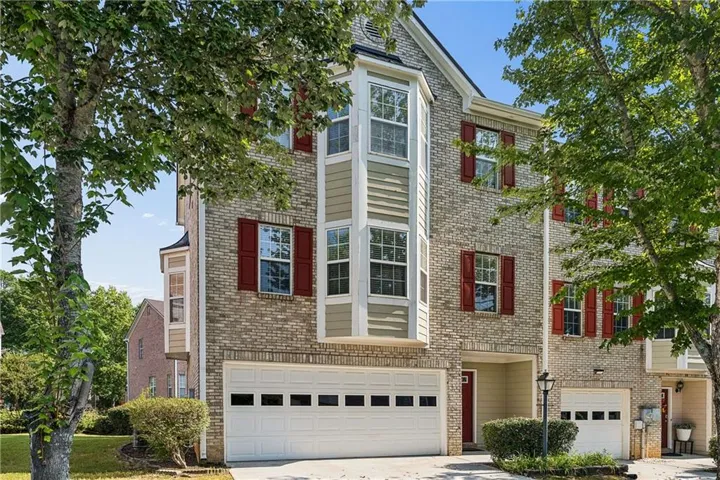 Brick exterior end unit with red shutters, a bay window feature, and a two-car garage