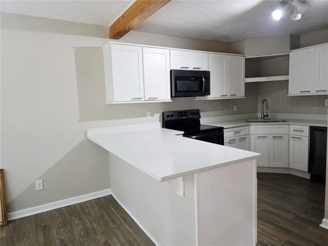 Modern kitchen featuring white shaker cabinetry, light-toned countertops, and wood-finish flooring